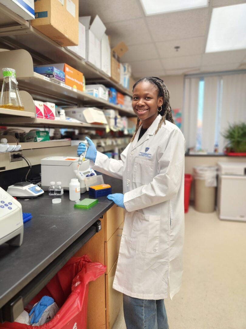 Female scientist in lab coat working with laboratory equipment in a laboratory setting.