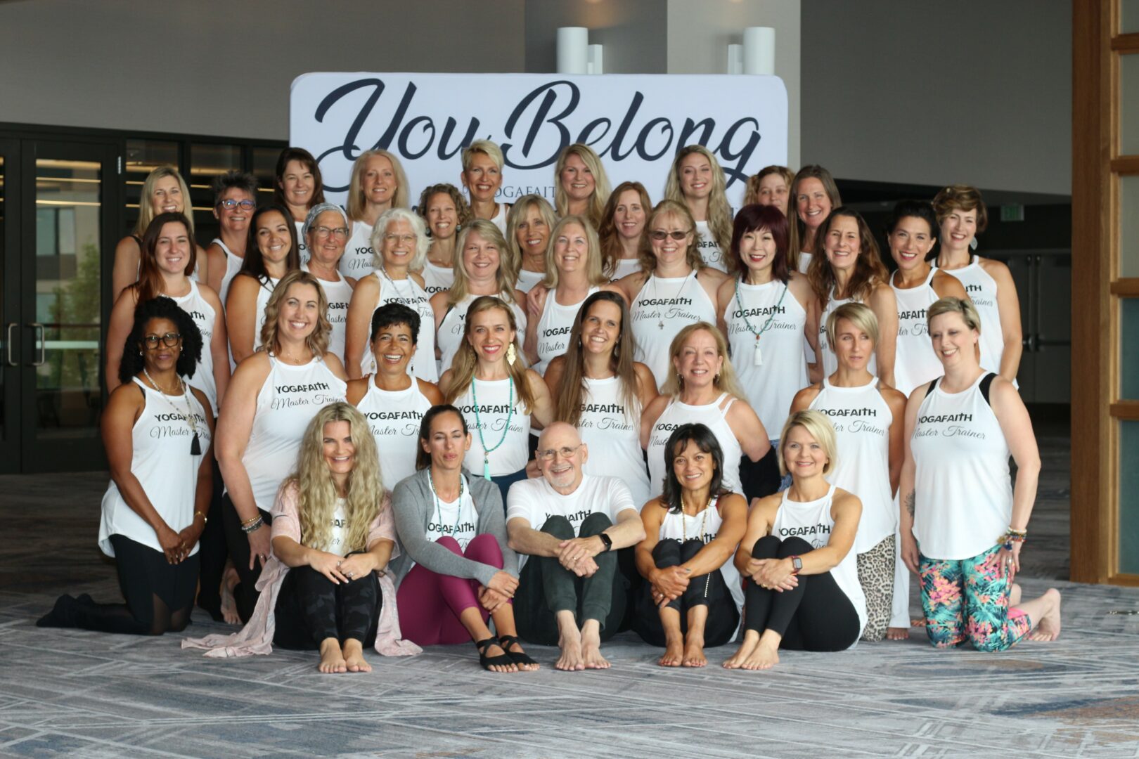 Group of women and girls posing in front of a sign that says 