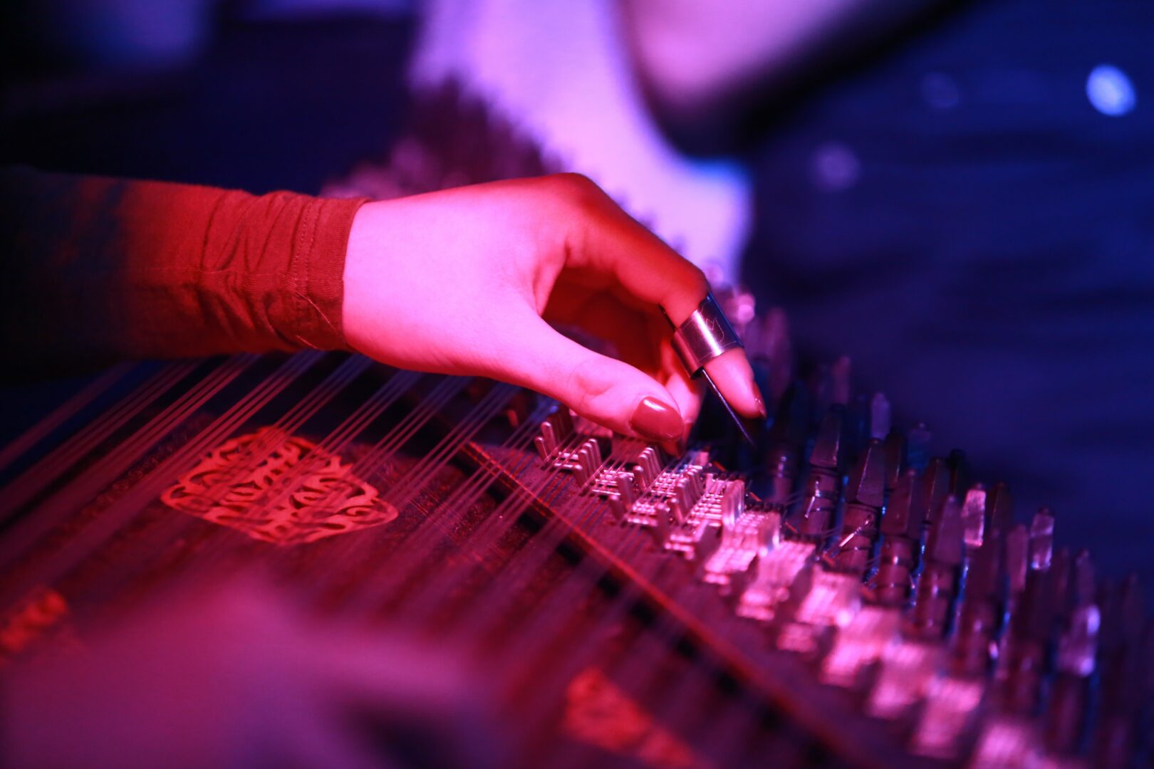 Hand adjusting sound mixer controls with colorful lighting, focus on fingers and equipment, background blurred.